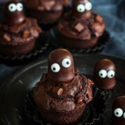 Schokoladenmuffins mit Schokoladenbonbons, dekoriert als gruselige Kreaturen mit Glupschaugen, angerichtet auf dunklen Tellern - perfekt für Ihr nächstes Halloween-Rezept oder um ein lustiges neues Muffin-Rezept auszuprobieren!.