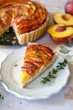 Angeschnittene Pfirsichtarte mit Thymianzweig