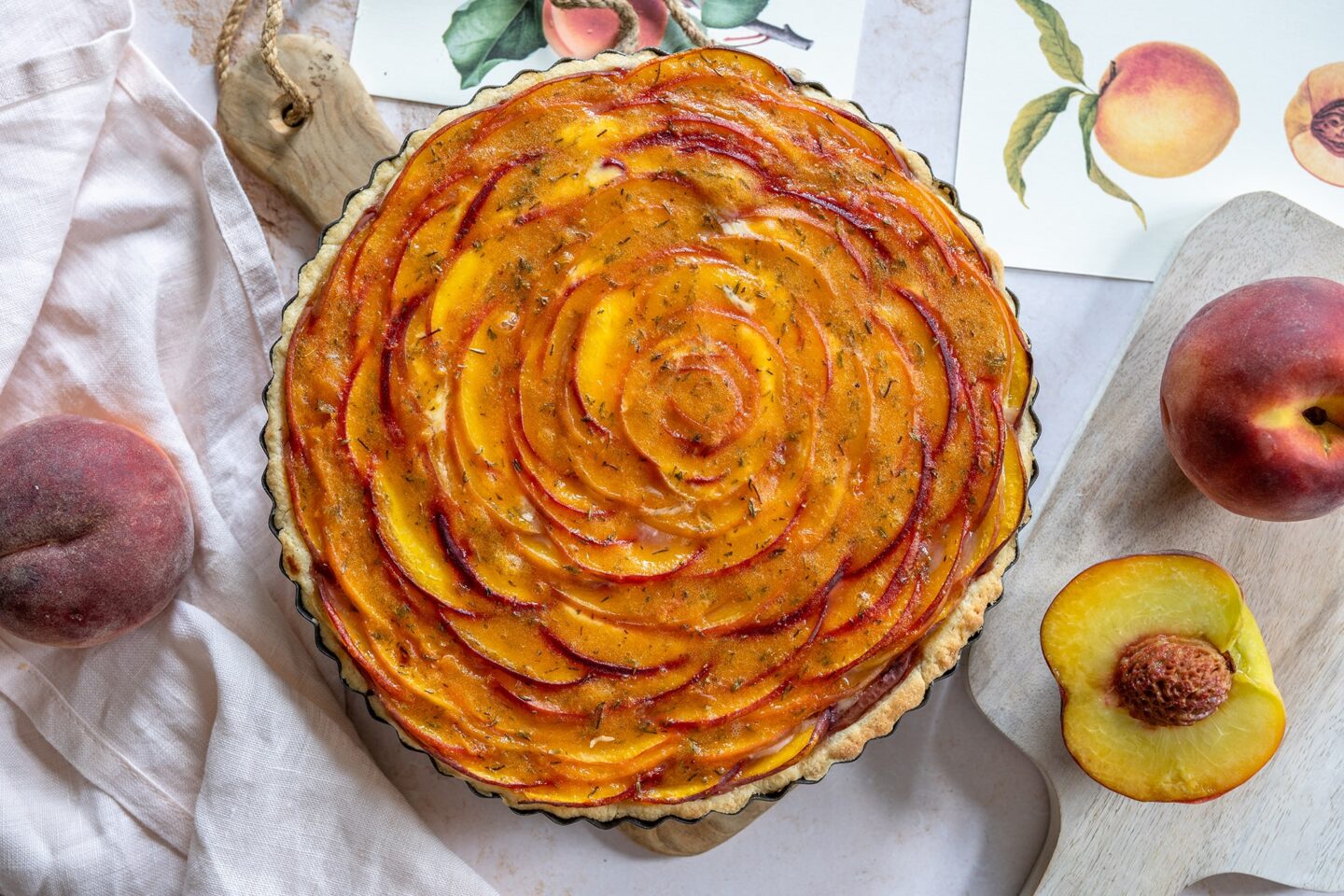 Pfirsichtarte mit Thymian, Pfirsichspalten sind geschichtet und angeordnet wie die Blüten einer Blume.