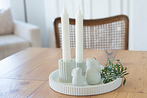 Das Nordlicht - handgemachtes Osterset im skandinavischen Stil mit zwei weißen Kerzen, Keramikhasen und Grünzweig auf einem Tablett bildet perfekte nordische Osterdeko als Frühlingsdekoration auf hellem Holztisch.