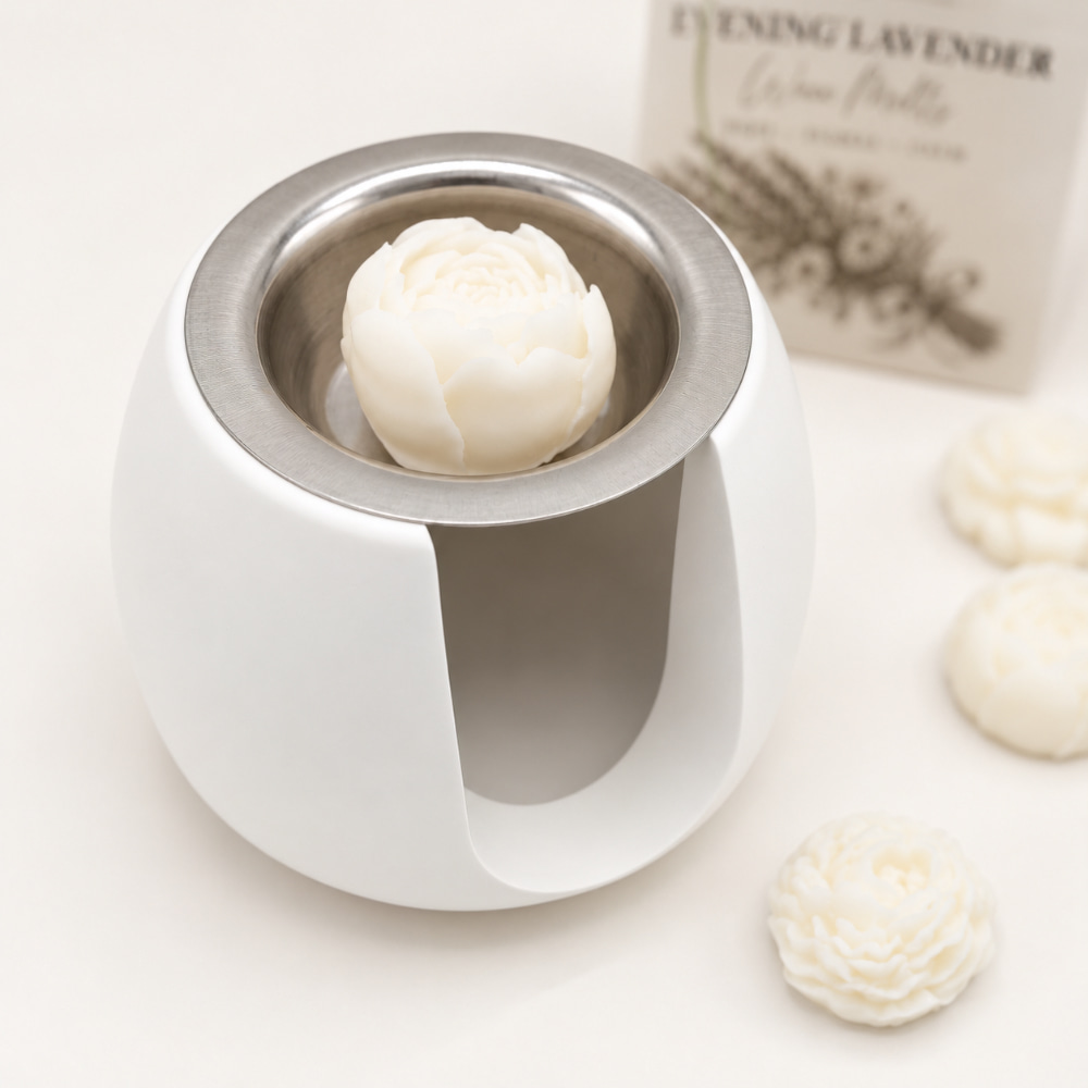 Nordic Ro, handgefertigte Duftlampe für Wachs-Melts und Duftöl, bestehend aus einem weißen Keramik-Wärmer, einem blumenförmigen Wachs-Melts in einer Stahlschale, drei weiteren Melts sowie einer Schachtel mit Evening Lavender-Wachs-Melts.